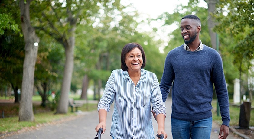 Man and senior woman using a walker outside walking down the street