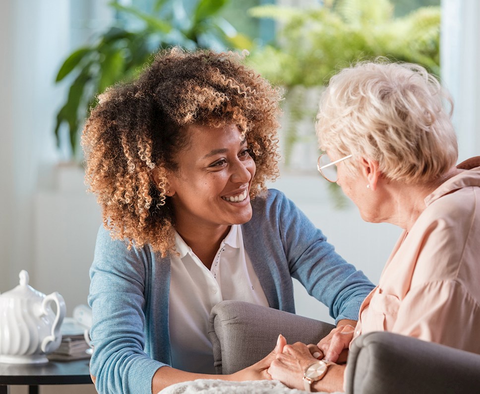 Female occupational therapist talking with elderly client and smiling