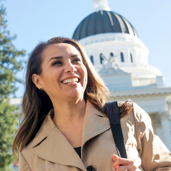 Smiling professional woman holding purse with state government building in background
