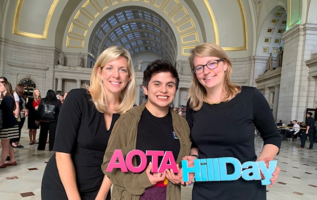 OT students smiling holding AOTA Hill Day sign inside building