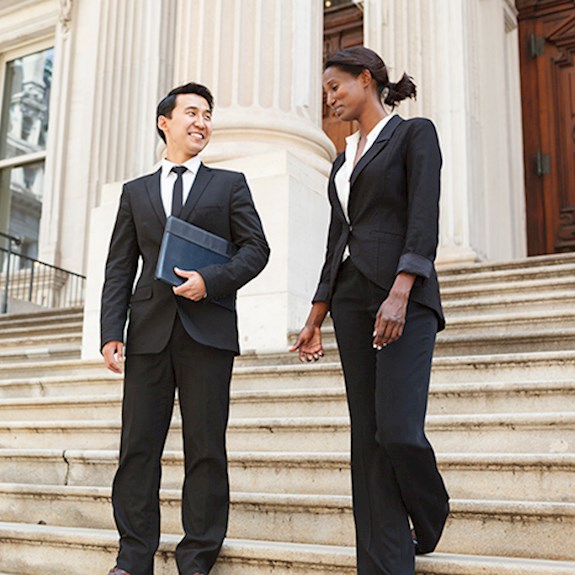 Professionally dressed man and woman walking down government building steps