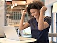 Woman celebrating with two clenched fists in the air looking at open laptop screen inside office