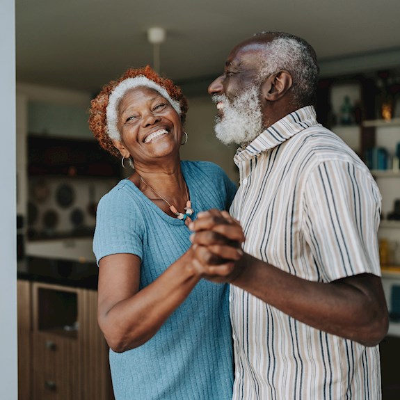 Image of an older African American couple smiling and dancing.