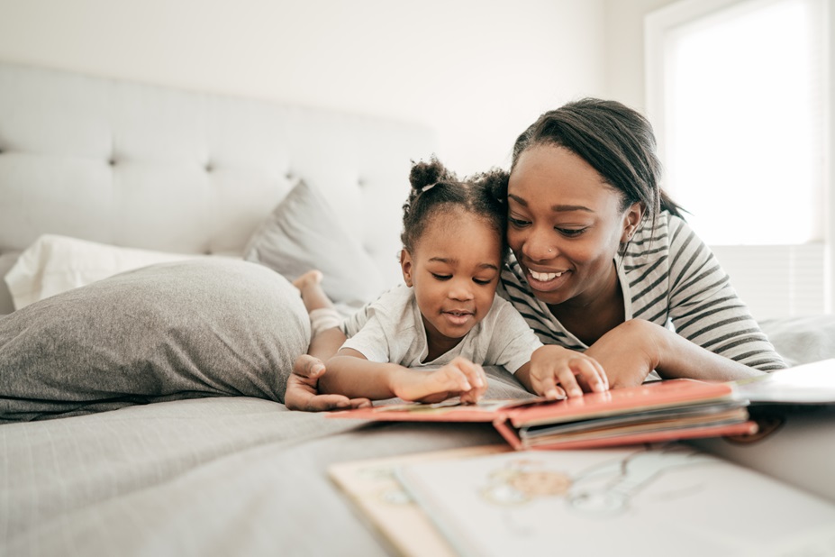 Adult reading a book to a child in bed