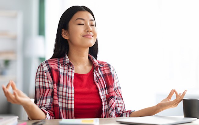 Woman with eyes closed meditating at desk