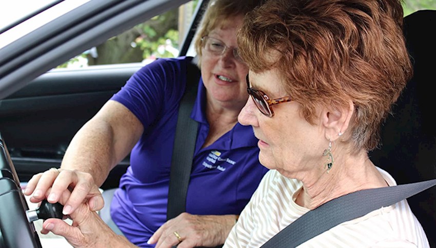 Female older driver working with occupational therapist and an adaptive steering wheel