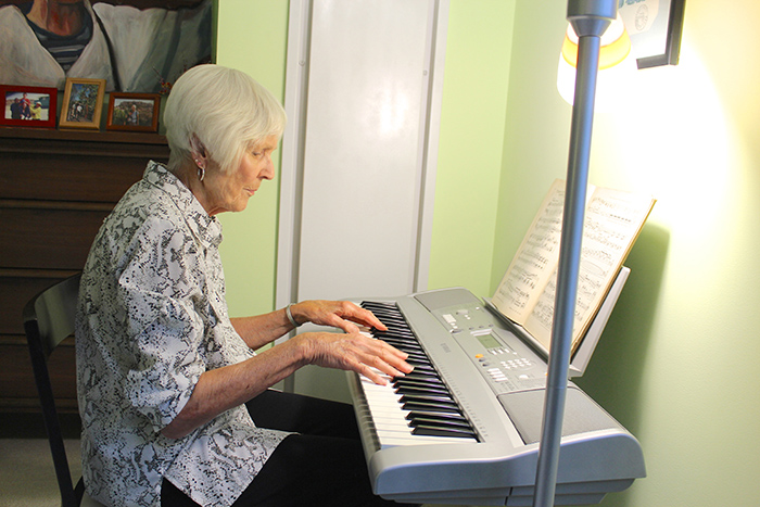 Senior woman at home playing electric piano keyboard