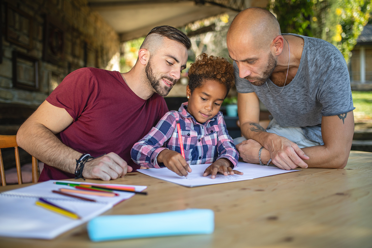 lgbtqia-two-dads-at-table-with-child-writing-on-paper