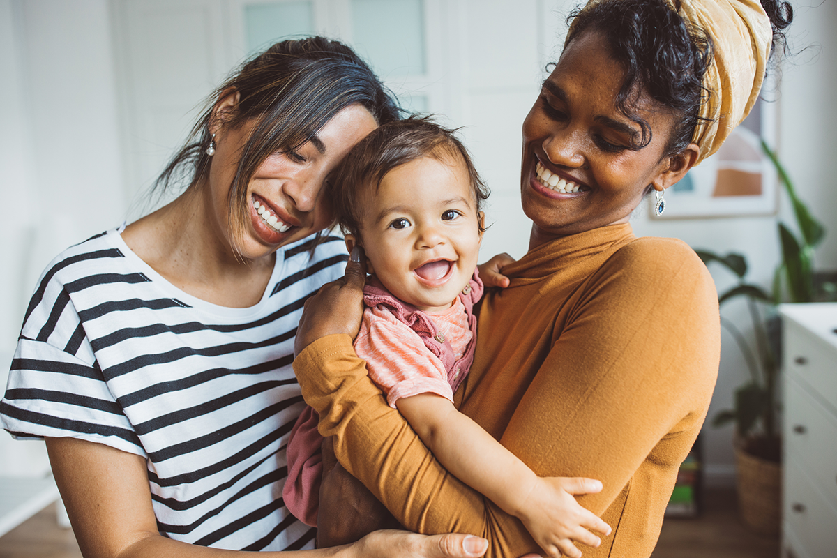 lgbtqia-two-smilng-moms-holding-happy-baby-girl