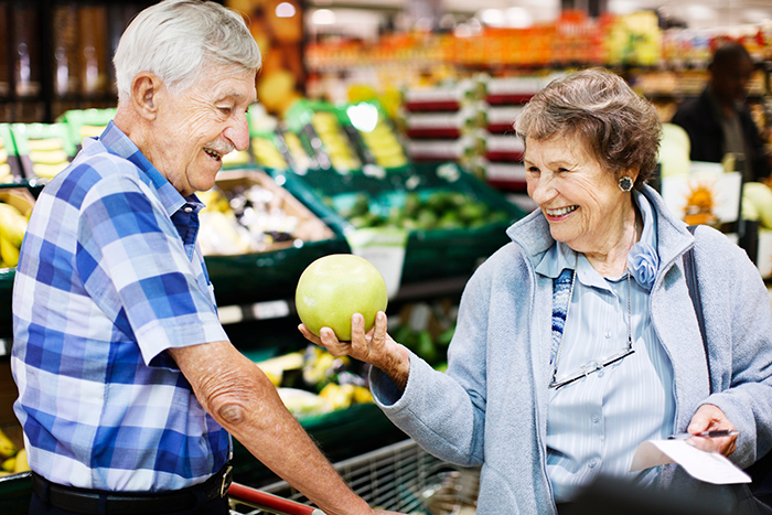 Older man and woman holding melon at grocery store shopping