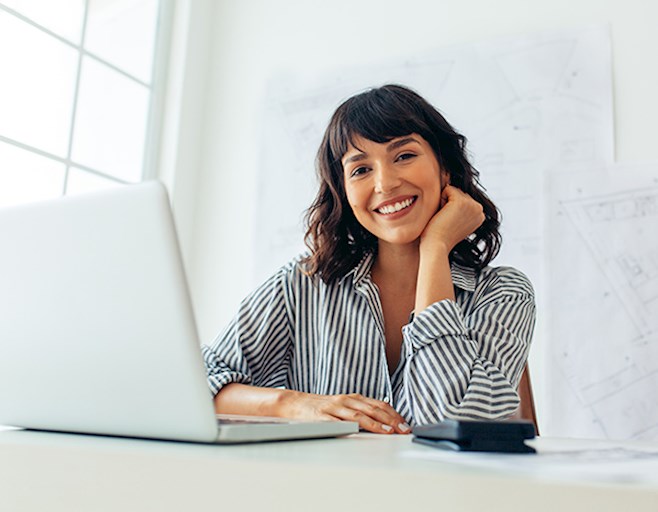 Smiling professional woman sitting behind open laptop
