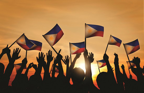 Hands in the air holding Filipino flags