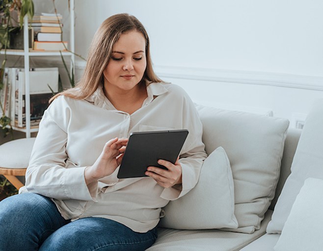 Woman sitting on couch reading tablet