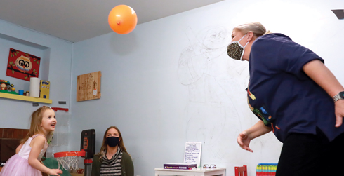 Child and grandmother enjoy a game of "balloon bat" as they coordinate passing a balloon back and forth without letting it touch the ground.