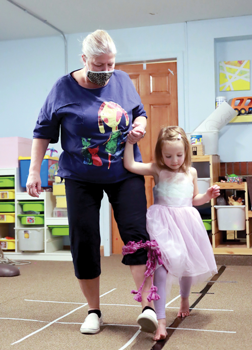 Child and grandmother participate in three-legged race to address skills related to coordination, balance, body awareness, and problem solving.