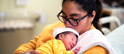 Woman with glasses holding baby on her shoulder