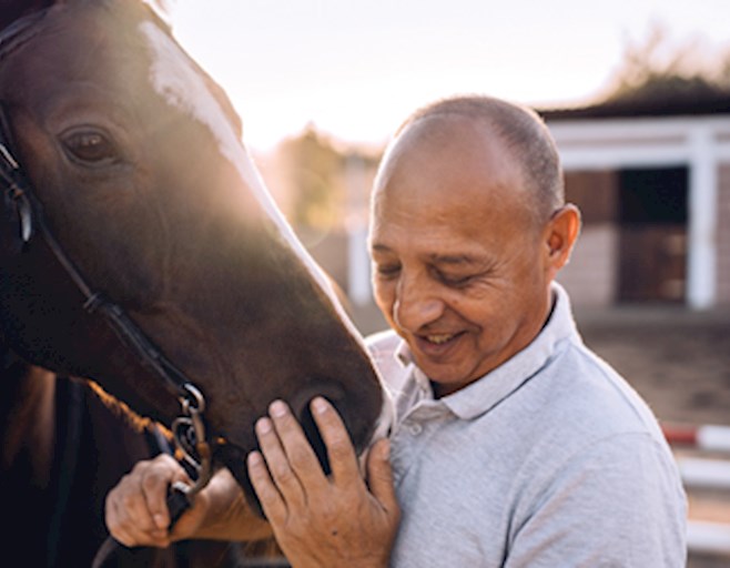 Man touching horse's face and smiling