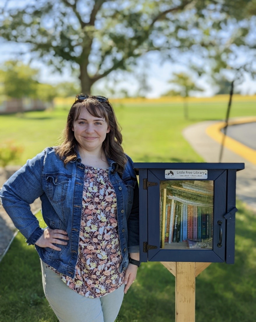 Student Amy Hodel standing next to a Little Free Library